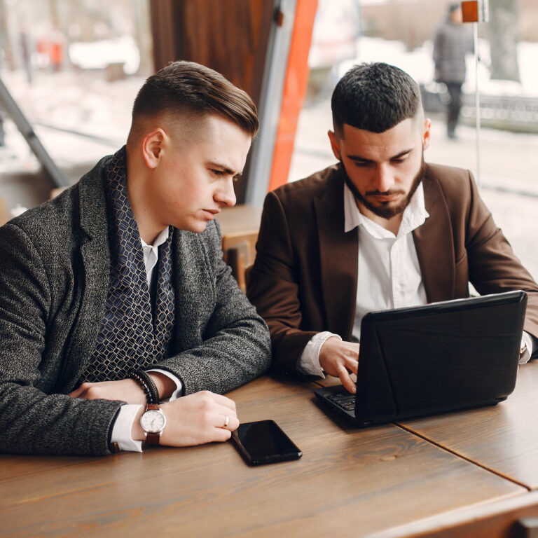 Two handsome men working. Friends in a cafe. Man in a suit with laptop